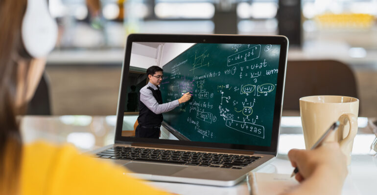 Rear View of Asian student learning with teacher over the physics formular in thai laguage on black board via video call conference when Covid-19 pandemic, education and Social distancing concept