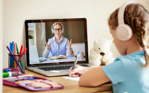 Girl listening to friendly teacher during online lesson