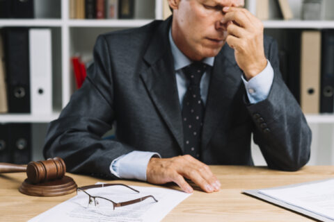 close-up-exhausted-male-mature-lawyer-sitting-front-desk