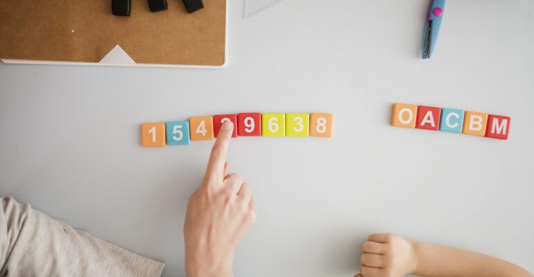 vue-de-dessus-du-tuteur-enseignant-a-l-enfant-au-bureau-les-chiffres-et-les-lettres